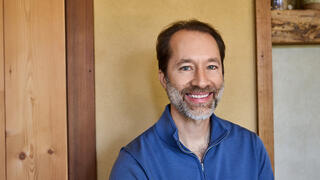 Earik Beann, Founder and CTO smiles against a rustic background, wearing a blue sweater.